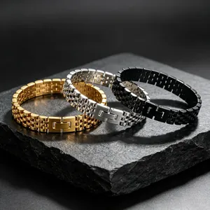 Gros plan de bracelets à maillons en acier inoxydable doré, argenté et noir sur pierre