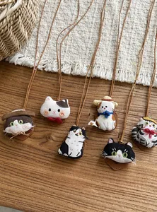 Handcrafted cloth doll cat necklaces with leather cords on a rustic wooden background