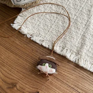 Close-up detail of a cute handmade fabric cat pendant necklace on a brown cord