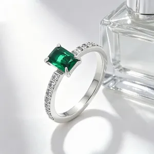 Detailweergave van een smaragdgeslepen groene zirkonia ring met zijstenen op roestvrij staal