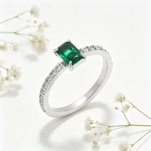 Gedetailleerd zijaanzicht van een ring met groene zirkoon en pavégezette roestvrijstalen band.