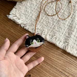 Detailed view of a cute handmade fabric cat pendant necklace on a leather cord.