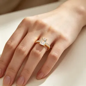 Detailopname van een ring met smaragdgeslepen steen en pavé-kristallen op goud.