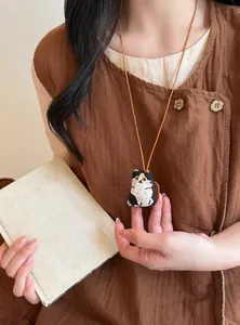 Close-up of a sweet and cute fabric cat doll pendant on a brown leather cord necklace.