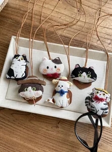 Detailed view of cute handmade cat embroidery necklaces with leather cords on a tray.