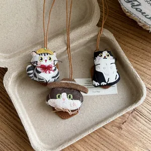 Detail view of cute embroidered cat doll necklaces with leather cords and fabric textures.