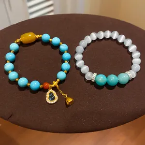 Dettaglio dei braccialetti con perline di turchese placcati oro 24 carats e ciondolo zucca.
