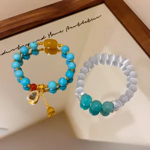 Dettaglio di braccialetti di perline di turchese e occhio di gatto placcati oro 24k con charm