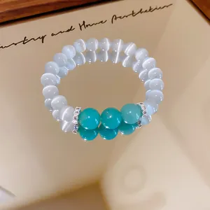 Dettaglio macro del bracciale con perline turchesi e occhio di gatto bianco