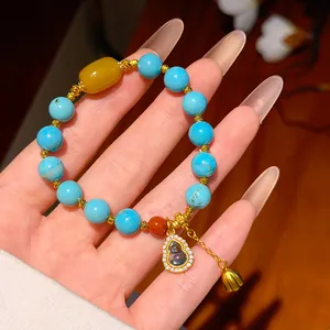 Primo piano di un bracciale di perline turchesi placcato oro 24k con ciondolo hulu