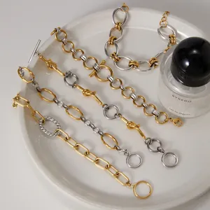Dettaglio di bracciali a catena in acciaio inossidabile bicolore oro e argento su piatto