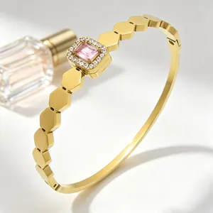 Elegante Nahaufnahme eines goldenen hexagonalen Armreifs mit rosa Edelstein und Kristall-Halo