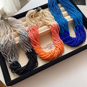 Multi-layer handmade seed bead necklaces with ombre gradient colors on a display tray