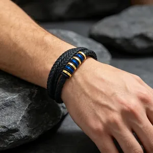 Gros plan d'un bracelet en cuir tressé double pour homme avec intercalaires en acier bleu et or.