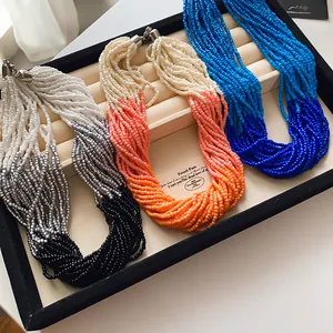 Detailed view of multi-strand seed bead necklaces in orange and blue on a display tray