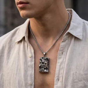 Detail view of a gothic stainless steel necklace with Buddha and demon face pendant