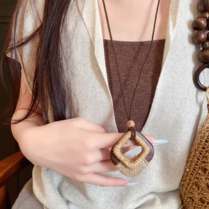 Close-up van vintage Boheemse ketting met houten en henneptouw hanger op een linnen top.