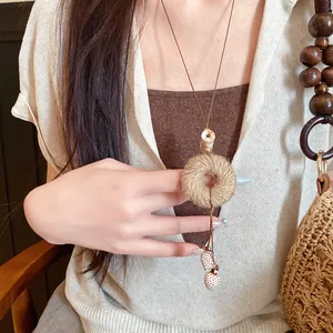 Close-up van Boheemse jute touw ketting met ronde hanger gedragen door een model.