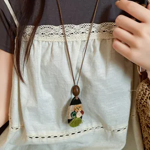 Lange koordketting in boho-stijl met kleurrijke knopen en groene kwastjes hanger