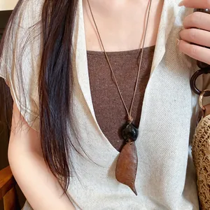 Gedetailleerde close-up van een Boheemse retro houten ketting met bladpendel op een vrouwelijk model