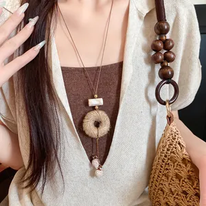 Detail van een bohemian retro ketting met leren koord en henneptouw hanger op model.