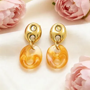 Close-up of French vintage resin pig nose earrings with gold finish and amber texture