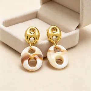 Close-up of French retro pig nose earrings with gold metal and marbled resin textures