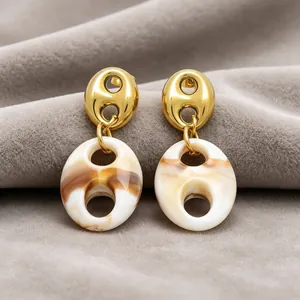 Close-up of French retro marbled resin pig nose drop earrings in gold and brown