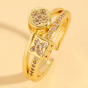 Dettaglio di anello aperto in acciaio dorato con charms a quadrifoglio in zircone.