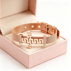 Close-up of rose gold stainless steel mesh bracelet with Greek key cross and pavé diamonds.