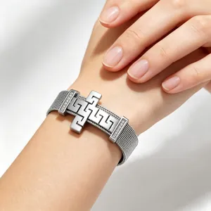 Close-up detail of a silver stainless steel mesh bracelet with a Greek fret cross design
