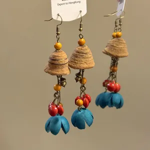 Détail rapproché de boucles d'oreilles à pompons ethniques avec fleurs et baies rouges