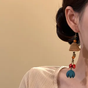 Gros plan de boucles d'oreilles ethniques avec graines et détail de fleur bleue