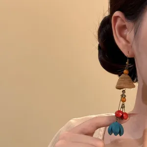 Boucle d'oreille ethnique faite main avec fruit de plante et fleur bleue.