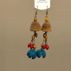 Vue détaillée de boucles d'oreilles ethniques avec glands en graines naturelles et fleurs bleues