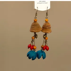 Vue détaillée de boucles d'oreilles ethniques avec graines naturelles et glands.