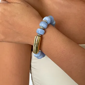 Nahaufnahme blauer Marmor-Acrylperlen und goldener Metallakzente am elastischen Armband
