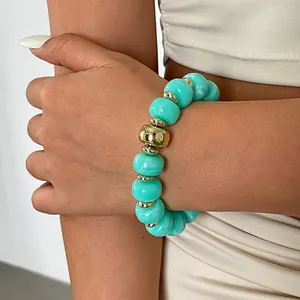 Auffälliges Armband mit türkisfarbenen Acrylperlen und goldenen Akzenten.