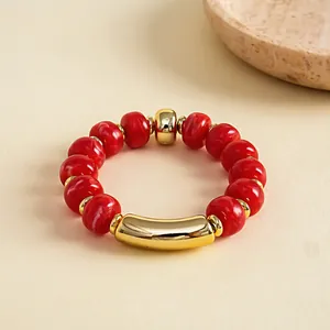 Detailansicht der roten Acrylperlen und des goldenen Metallelements an dem Armband