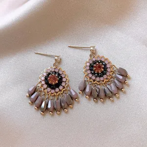 Close-up of ethnic glass tassel earrings with intricate beadwork and geometric charms