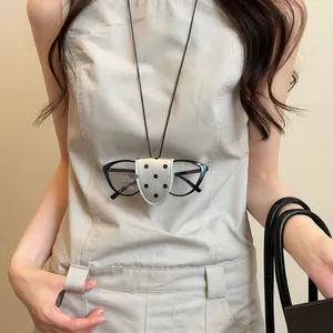 Close-up view of a stylish polka dot leather magnetic glasses clip necklace worn on a model.
