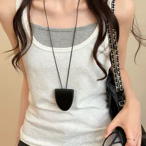 Close-up detail of a minimalist black leather magnetic eyeglass clip necklace on a model