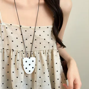 Close-up of a white polka dot leather magnetic glasses clip necklace worn on a model