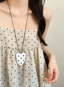 Detail shot of a white polka-dot leather magnetic sunglasses holder necklace on a model.