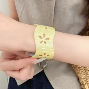 Macro view of stylish yellow acrylic hollow flower cuff bracelet on a model's wrist