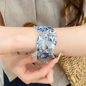 Detailed view of an acrylic hollow flower open bangle with blue marbled pattern on wrist
