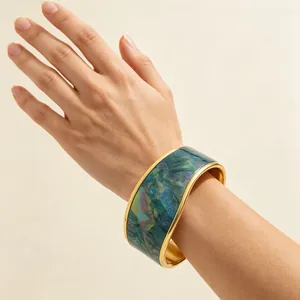 Detailed view of a wide gold-plated cuff bracelet with vibrant oil painting style texture