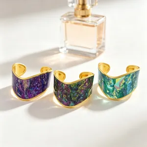Close-up of V-shaped gold-plated cuff bracelets with vibrant oil painting textures.