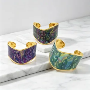 Close-up of three wide gold-plated V-shaped cuffs with vibrant artistic oil-painting textures