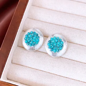 Elegantes pendientes redondos de plata con cuentas turquesas en un joyero